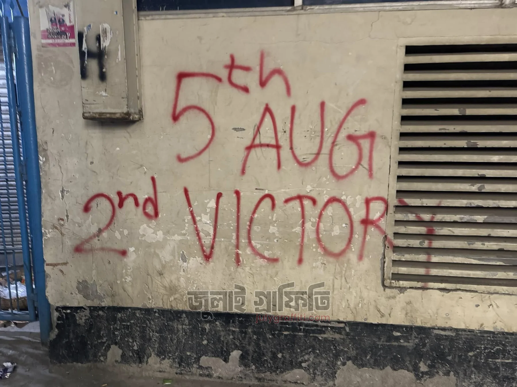 Red spray-painted graffiti on a wall in Dhaka reading 5th Aug, 2nd Victory